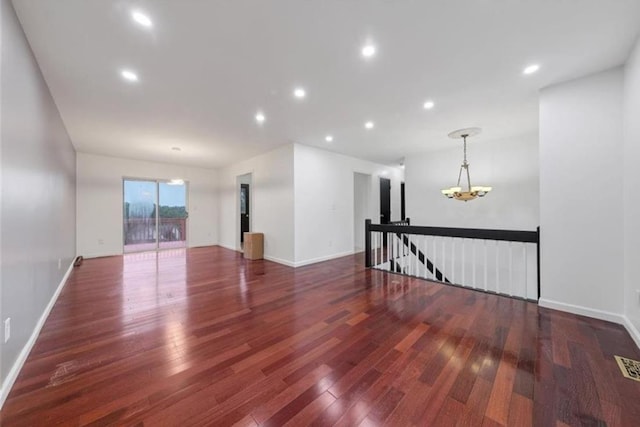 unfurnished room featuring dark hardwood / wood-style flooring and an inviting chandelier