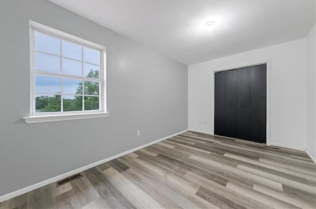 unfurnished bedroom with light wood-type flooring and a closet