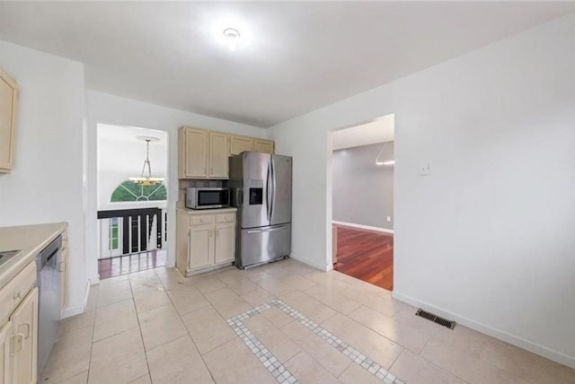 kitchen featuring light tile patterned floors, stainless steel appliances, and cream cabinets