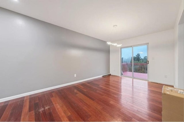 empty room with a notable chandelier and hardwood / wood-style flooring