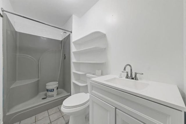 bathroom with tile patterned flooring, vanity, toilet, and walk in shower