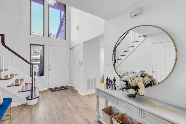 entryway featuring light hardwood / wood-style floors and a towering ceiling