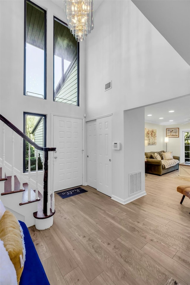 foyer entrance featuring hardwood / wood-style flooring, a high ceiling, and a notable chandelier