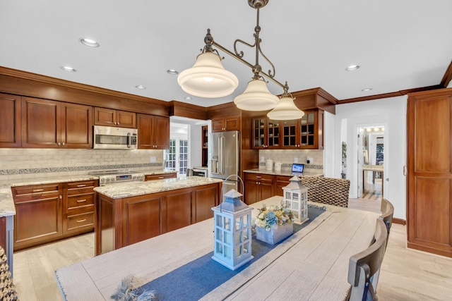 kitchen with pendant lighting, light wood-type flooring, light stone counters, a center island, and stainless steel appliances