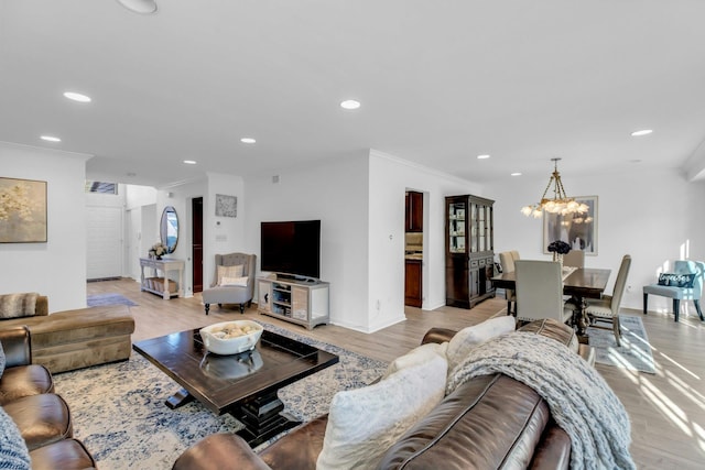 living room with ornamental molding, a chandelier, and light hardwood / wood-style flooring