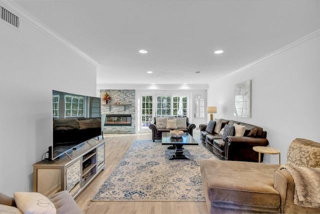 living room featuring crown molding, light hardwood / wood-style flooring, and a fireplace