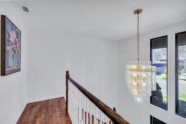 hall with a notable chandelier, a wealth of natural light, and dark hardwood / wood-style floors