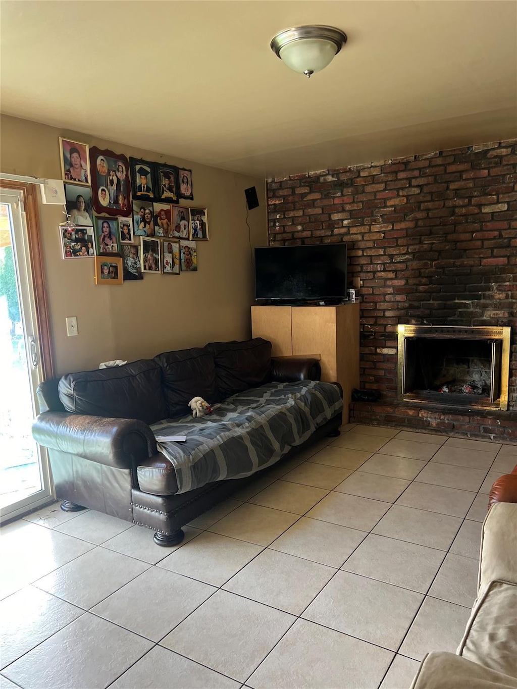 living room with light tile patterned flooring and a brick fireplace