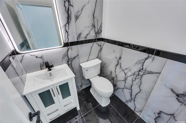 bathroom with vanity, toilet, and tile walls