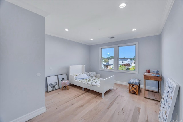 bedroom featuring light wood-type flooring and crown molding