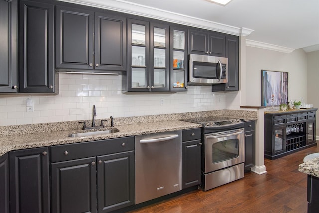 kitchen featuring dark wood-type flooring, sink, crown molding, light stone counters, and appliances with stainless steel finishes