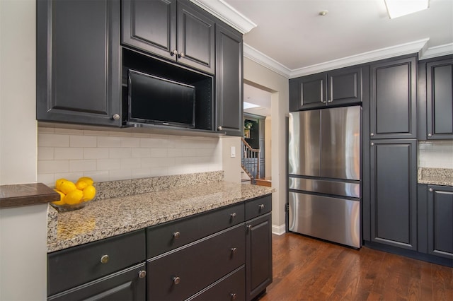 kitchen with light stone countertops, dark hardwood / wood-style floors, ornamental molding, and stainless steel refrigerator