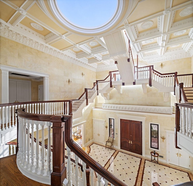 entrance foyer featuring hardwood / wood-style floors, a towering ceiling, crown molding, and coffered ceiling