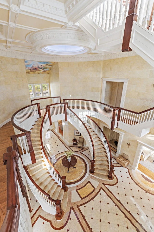 stairs with ornamental molding and coffered ceiling