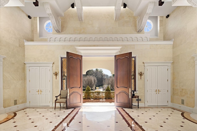 foyer entrance featuring beam ceiling, a towering ceiling, and light tile patterned floors