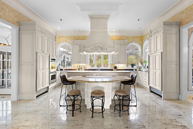 kitchen with sink, a center island, double oven, a breakfast bar, and ornamental molding