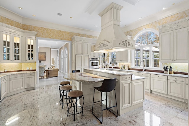 kitchen with light stone countertops, a center island, sink, oven, and a kitchen bar