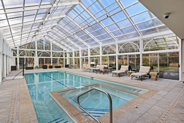 view of pool with outdoor lounge area, an in ground hot tub, a patio, and glass enclosure