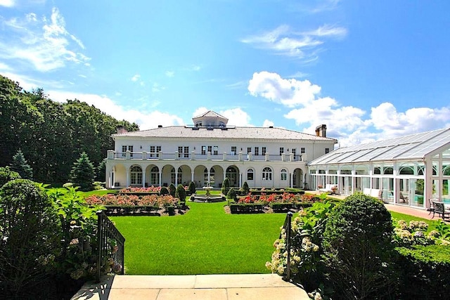 rear view of property featuring a yard and a balcony