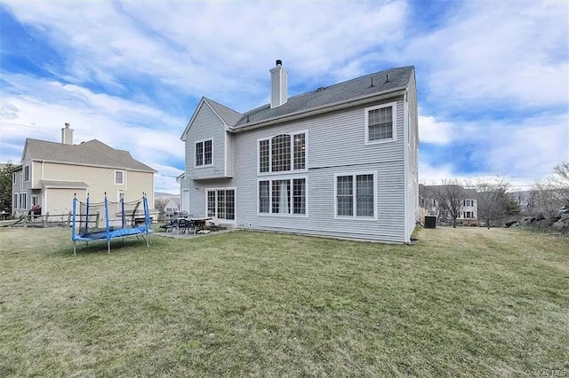 rear view of property featuring a lawn, central AC unit, a patio area, and a trampoline