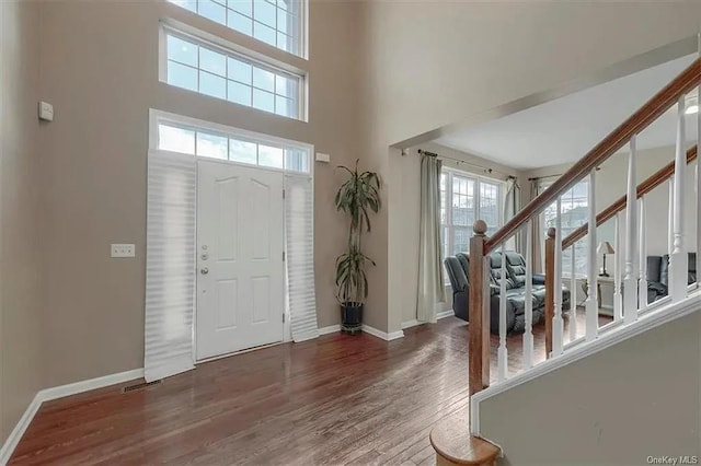 foyer featuring wood-type flooring and a towering ceiling