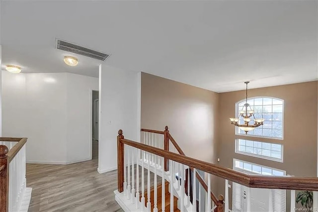 hall featuring light wood-type flooring and an inviting chandelier