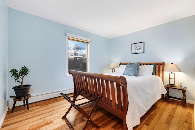 bedroom with a baseboard radiator and light hardwood / wood-style floors