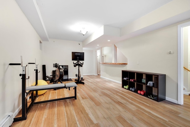 exercise area featuring baseboard heating and light hardwood / wood-style flooring