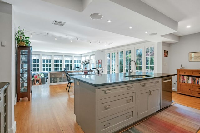 kitchen with a kitchen island with sink, dishwasher, sink, and light hardwood / wood-style floors