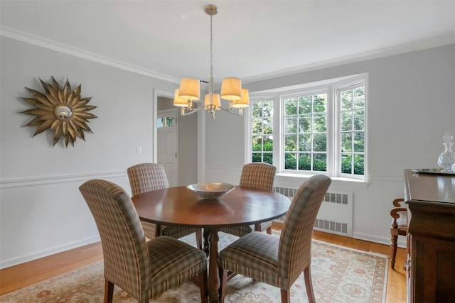 dining room featuring light wood-type flooring, ornamental molding, a chandelier, and radiator heating unit