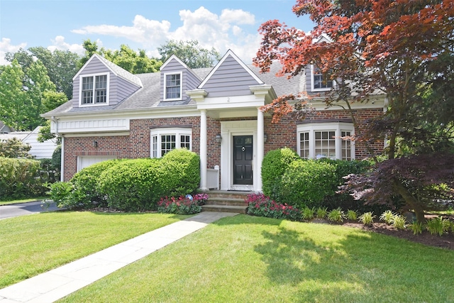 new england style home featuring a garage and a front yard