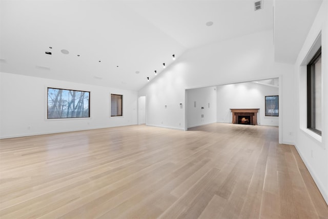 unfurnished living room featuring high vaulted ceiling and light wood-type flooring