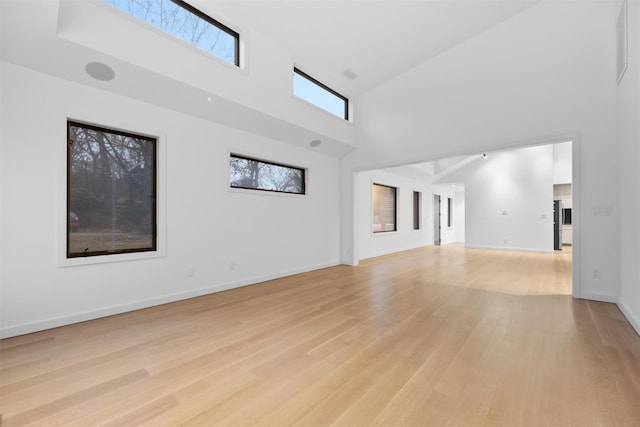 unfurnished living room featuring a towering ceiling and light hardwood / wood-style floors