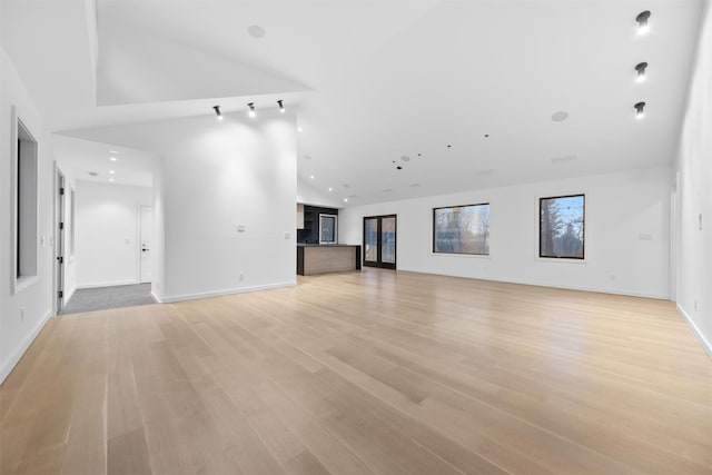 unfurnished living room with high vaulted ceiling and light wood-type flooring