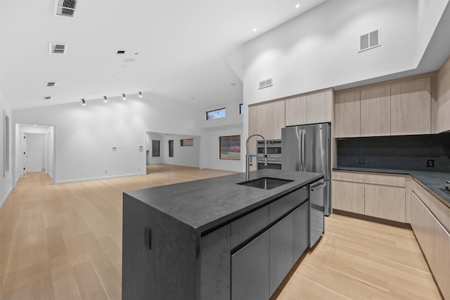 kitchen with appliances with stainless steel finishes, sink, a center island with sink, and light brown cabinets