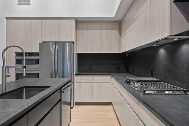 kitchen featuring light brown cabinetry, sink, light hardwood / wood-style floors, and appliances with stainless steel finishes