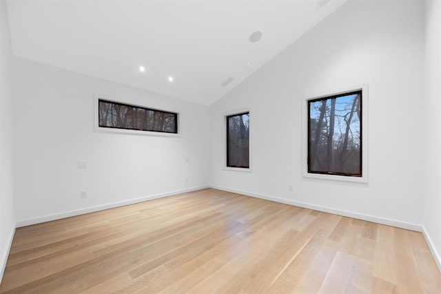 empty room with high vaulted ceiling and light hardwood / wood-style flooring