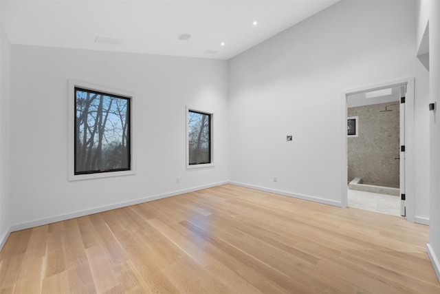 empty room featuring high vaulted ceiling and light hardwood / wood-style flooring