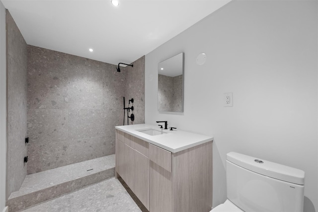 bathroom featuring vanity, toilet, and a tile shower