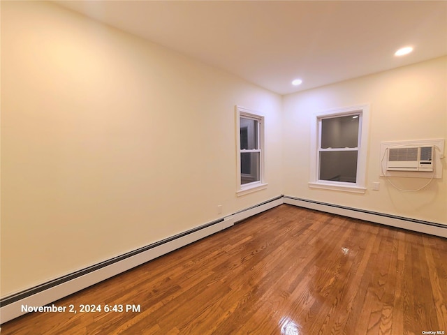 spare room featuring a wall mounted air conditioner, hardwood / wood-style flooring, and baseboard heating