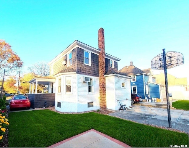 rear view of property with a wall unit AC and a yard