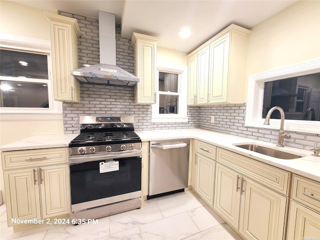 kitchen featuring sink, cream cabinets, wall chimney range hood, and appliances with stainless steel finishes