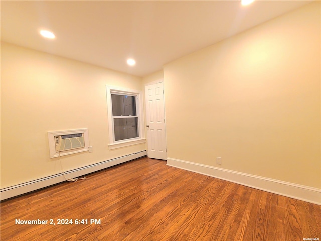 empty room featuring a wall mounted AC, hardwood / wood-style flooring, and baseboard heating