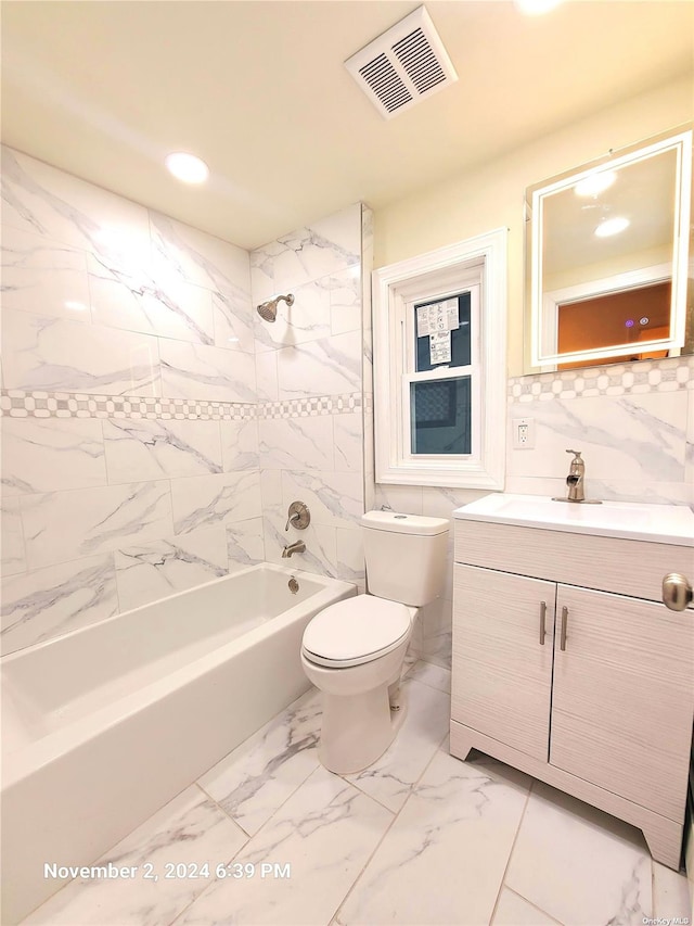 full bathroom with vanity, tiled shower / bath combo, tile walls, and toilet