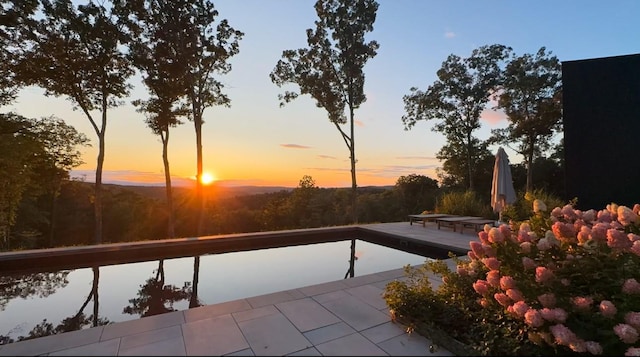 pool at dusk with a patio area