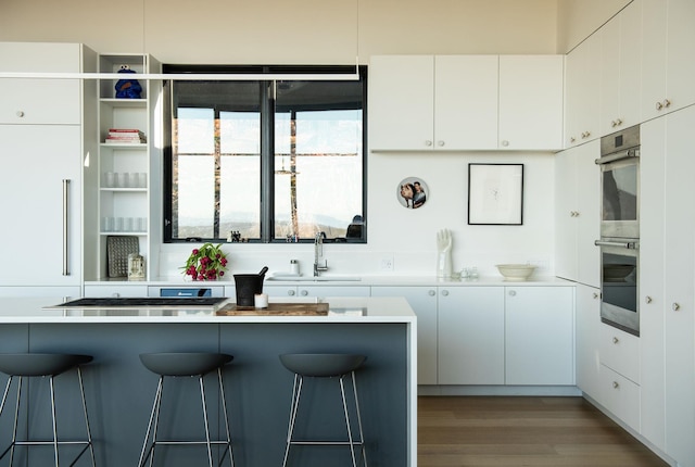 kitchen with white cabinets, a kitchen breakfast bar, and sink