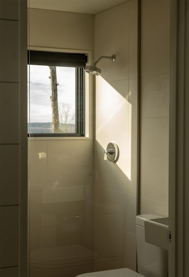 bathroom featuring a tile shower and toilet