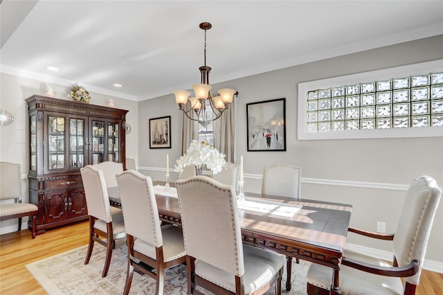 dining room featuring light wood-type flooring, an inviting chandelier, and ornamental molding