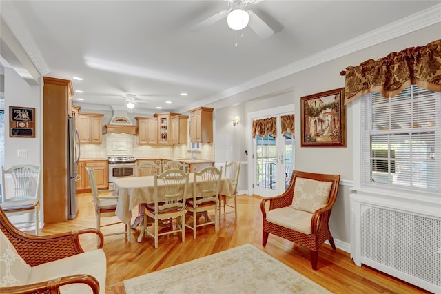 dining area with light hardwood / wood-style floors, crown molding, radiator, and a healthy amount of sunlight