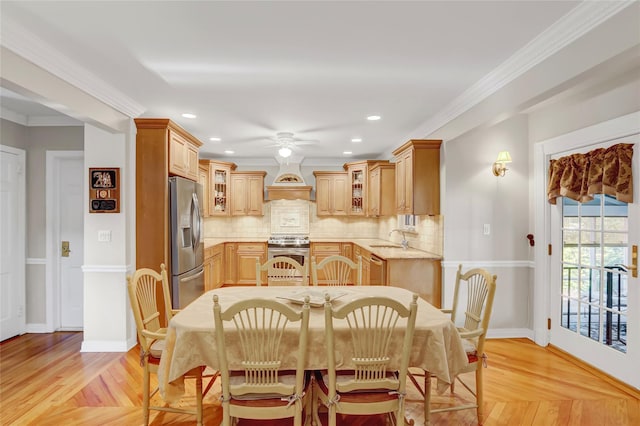 dining space featuring ceiling fan, sink, light parquet floors, and ornamental molding